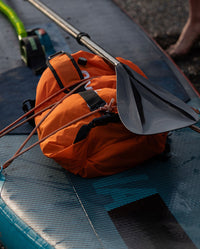 dryrobe Compression Travel Bag in Orange strapped on top of paddle board