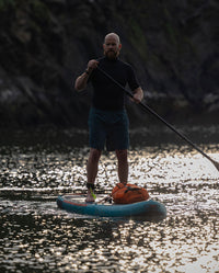 Man paddling on stand up paddle board, with dryrobe Compression Travel Bag strapped on the board