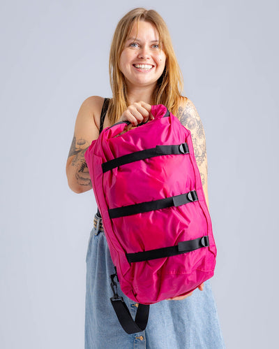 Woman in studio carrying hot pink Dryrobe® compression bag 