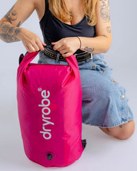 Woman in studio securing hot pink Dryrobe® compression bag 