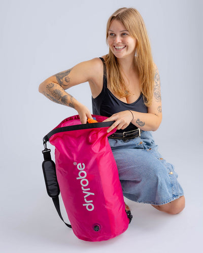 Woman in studio unpacking hot pink Dryrobe® compression bag 
