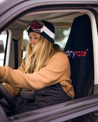 Woman smiling wearing ski goggles, sat in van on dryrobe Van Seat Cover in Black