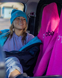 Woman sitting in a car with legs across seats, on Pink dryrobe® Water-repellent Car Seat Covers