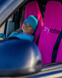 Woman wearing Blue dryrobe® Eco Beanie sitting in a car on Pink dryrobe® Water-repellent Car Seat 