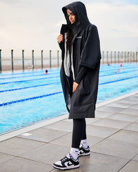 Woman stood next to a pool, wearing dryrobe® Lite changing robe