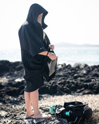 Woman stood on a beach, zipping up dryrobe® Lite changing robe