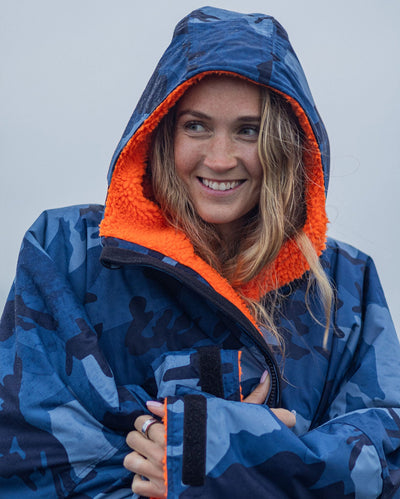 Close up of woman smiling, wearing Blue Camo Orange dryrobe advance long sleeve changing robe with hood up
 