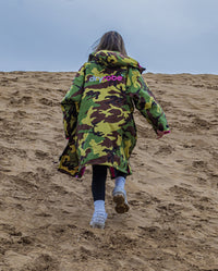 Girl walking up sand dune wearing Camo Pink dryrobe® Advance Kids Long Sleeve