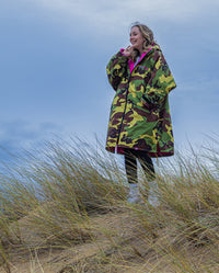 Girl stood on top of sand dune, wearing Camo Pink dryrobe® Advance Kids Long Sleeve