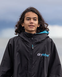 Close up of boy stood outdoors, wearing Black Blue dryrobe® Advance Kids Long Sleeve