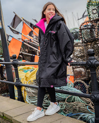 Girl leaning on railings, wearing Black Pink dryrobe® Advance Kids Long Sleeve