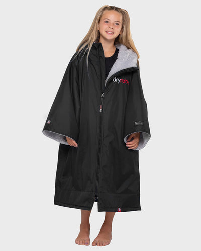 Girl smiling, wearing dryrobe Advance Kids Short Sleeve changing robe in Black Grey