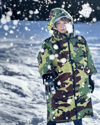 Boy stood in the snow, wearing dryrobe Advance Short Sleeve changing robe in Camo Grey