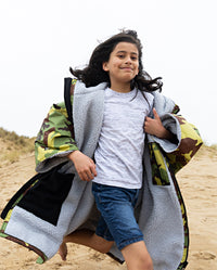 Child running down sand dune, wearing dryrobe Advance Short Sleeve changing robe in Camo Grey