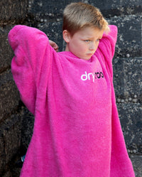 Boy stood in front of a wall, wearing Kids Towel Robe in Pink