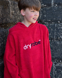 Boy stood by a wall, wearing Red Kids Organic Towel robe