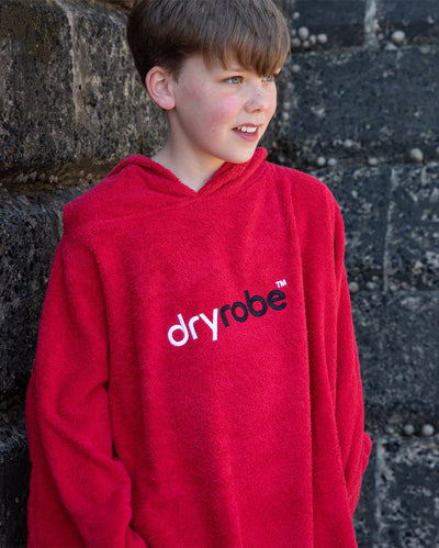 Boy stood by a wall, wearing Red Kids Organic Towel robe