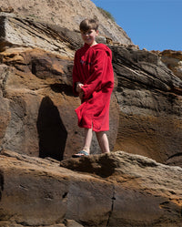 Boy walking along rocks, wearing Red Kids Organic Towel robe