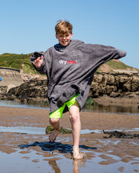 Boy running through water on the beach, wearing Kids Towel Robe in Slate Grey