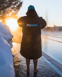 *MALE* stood on snowy poolside wearing Black Blue dryrobe® Advance Long Sleeve