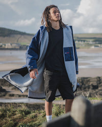 *MALE* stood by the beach, wearing Navy Grey dryrobe® Advance Long Sleeve, unzipped