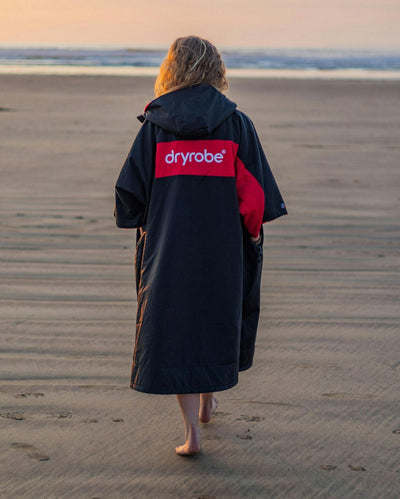 Adult female on beach wearing Dryrobe® Black red remix