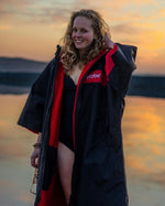 Adult female on beach wearing Dryrobe® Black red remix
